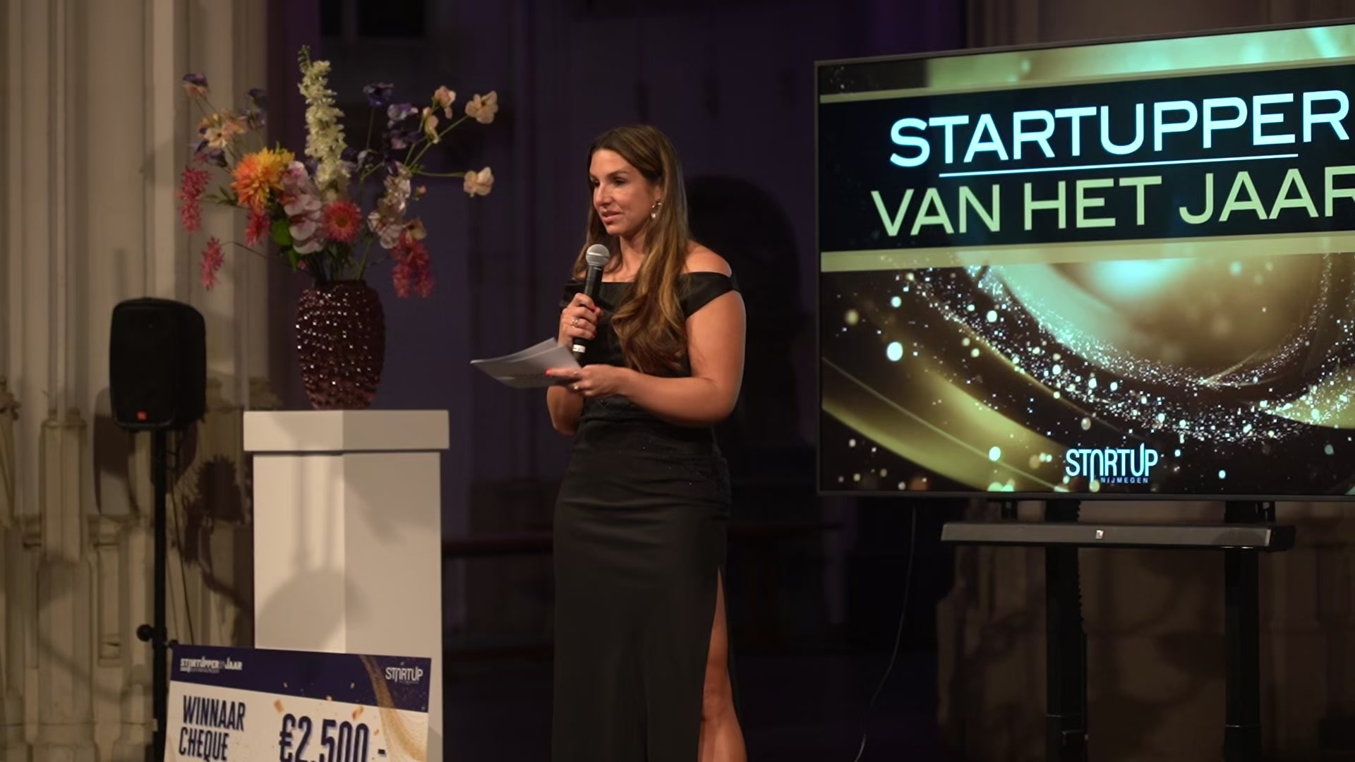 Carola Rodrigues Lopes op het podium met microfoon tijdens een award-uitreiking
